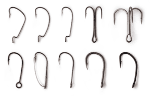 Different types of fishing hooks arranged on a background of sand